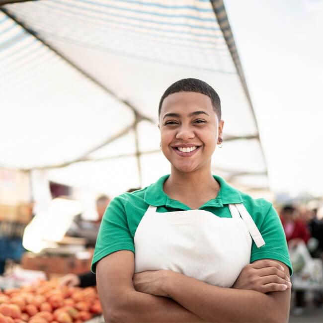 Person standing with crossed arms with market in background