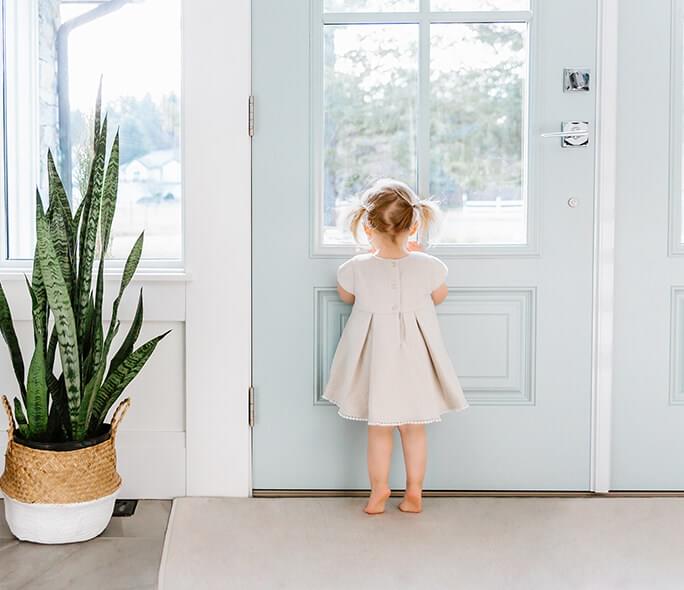 Little girl looking outside her front door window