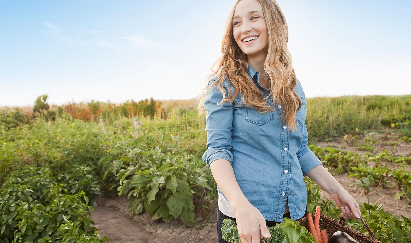 Woman hold basket of vegetables in a community garden