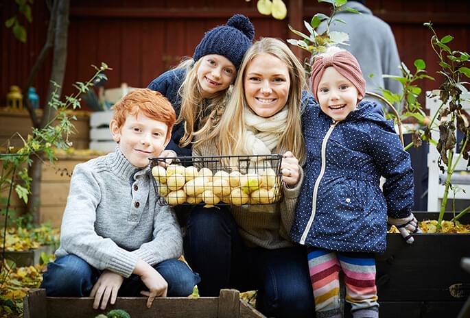 Woman and her 3 children holding a basket of potatoes