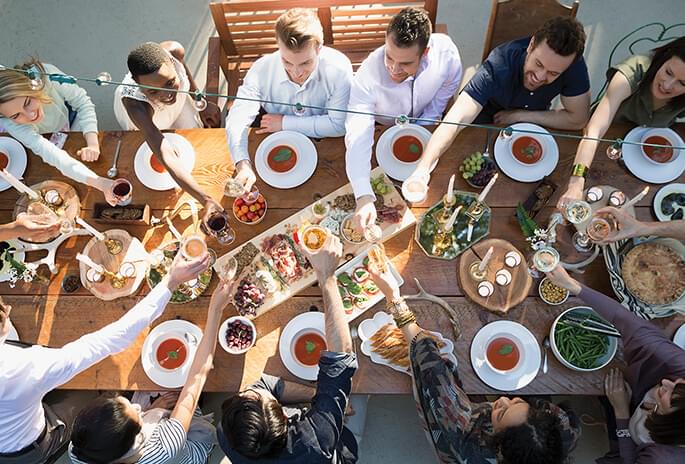 A group of people sitting at a large dining table toasting